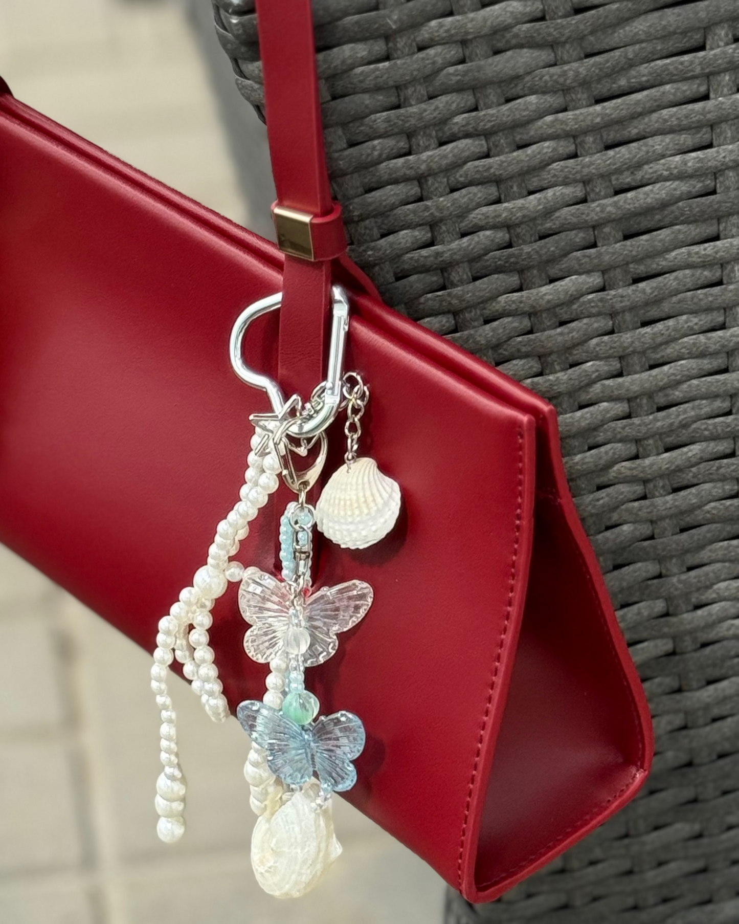 Decorative bag charm with beads and butterflies hanging from a red bag.